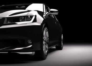 Modern new black metallic sedan car in spotlight. Generic contemporary desing, brandless. 3D rendering.